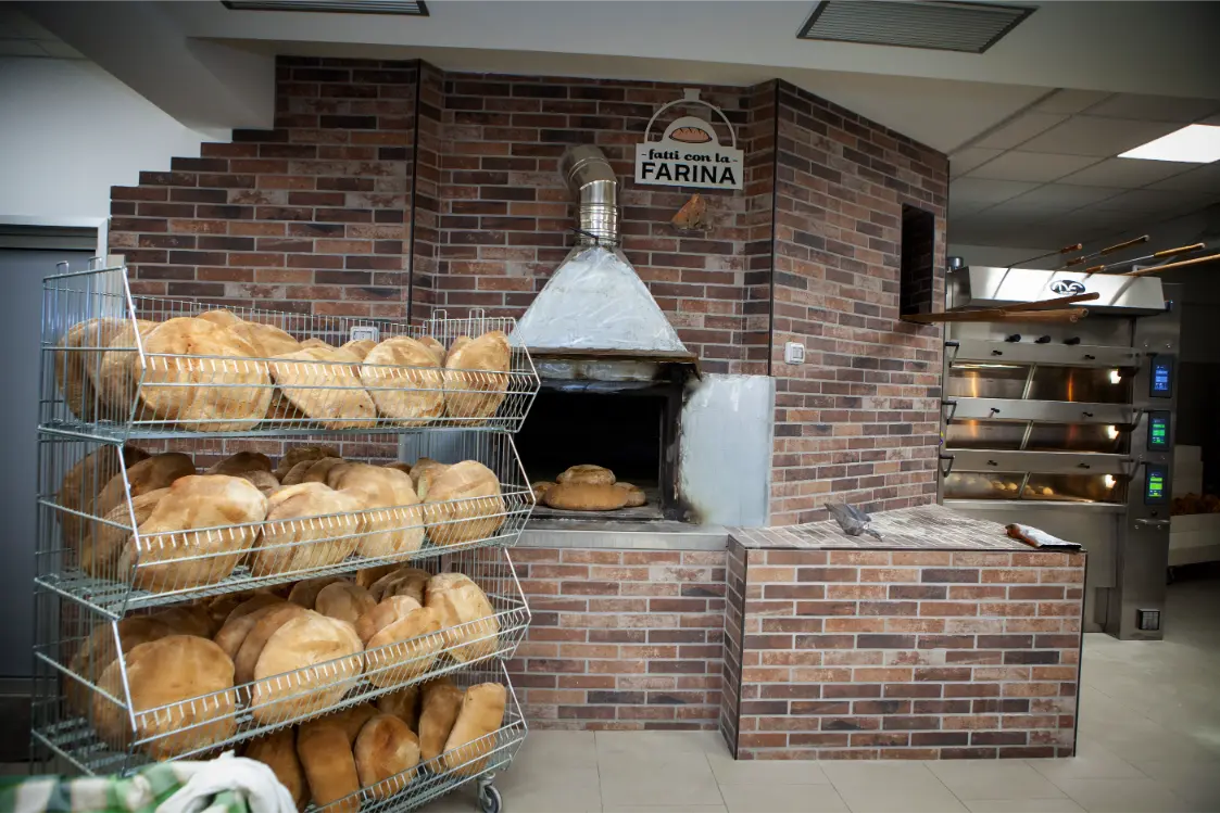 Forno a legna a mattoni con il pane in cottura nel panificio di Potenza