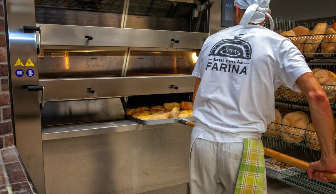 Panettiere che inforna il pane nel forno a legna a Potenza